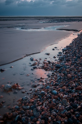 Oblázková pláž při západu slunce